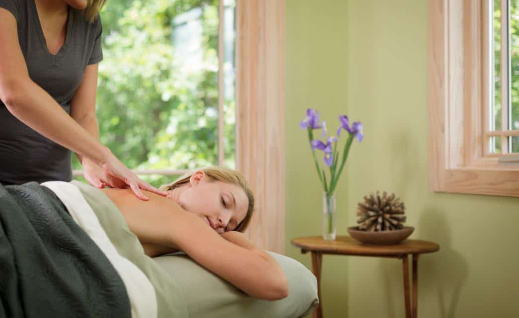 Woman under green sheets and blankets getting a massage