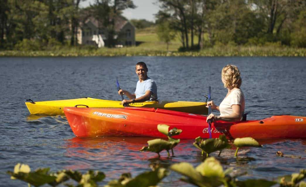 Man in yellow kayak next to woman in orange kayak floating on the water