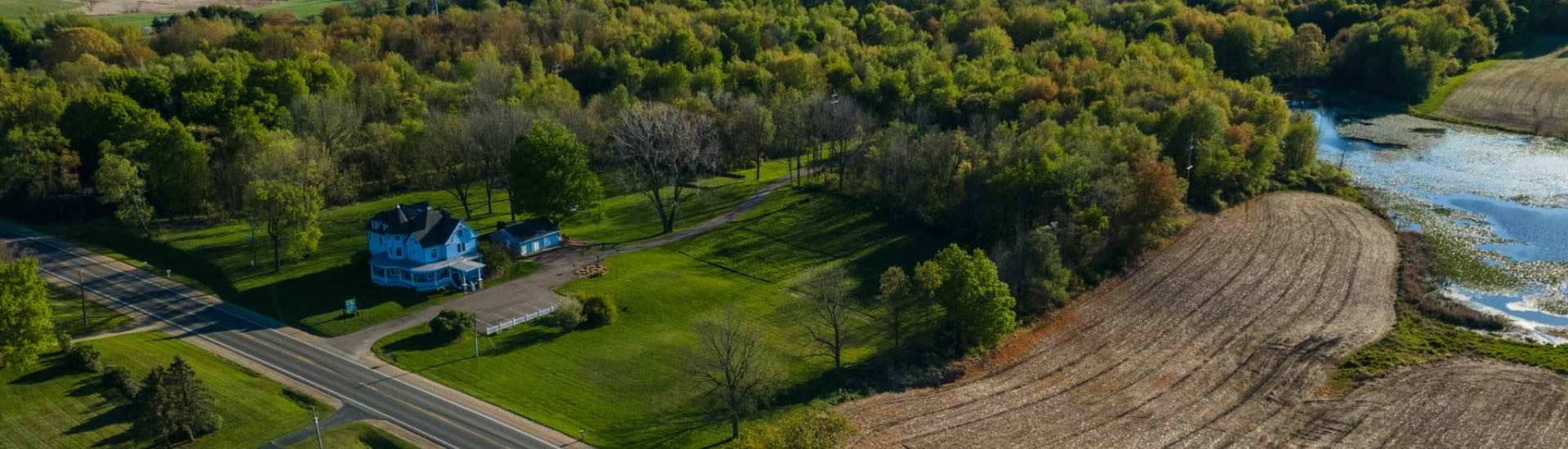 Aerial view of property surrounded by green grass and trees and small river