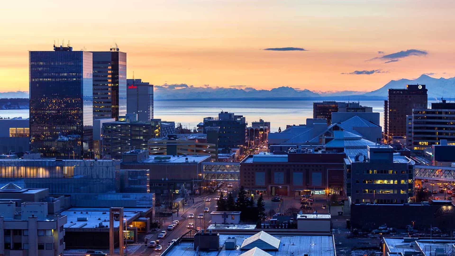 Aerial view of a city's downtown area near the water with mountains in the background