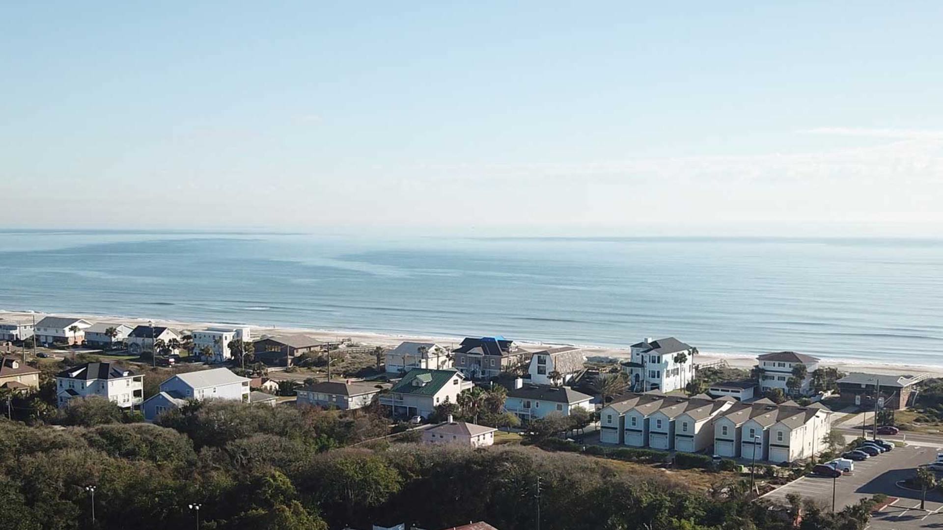 Aerial view of residential properties near the beach with ocean and sky in the background