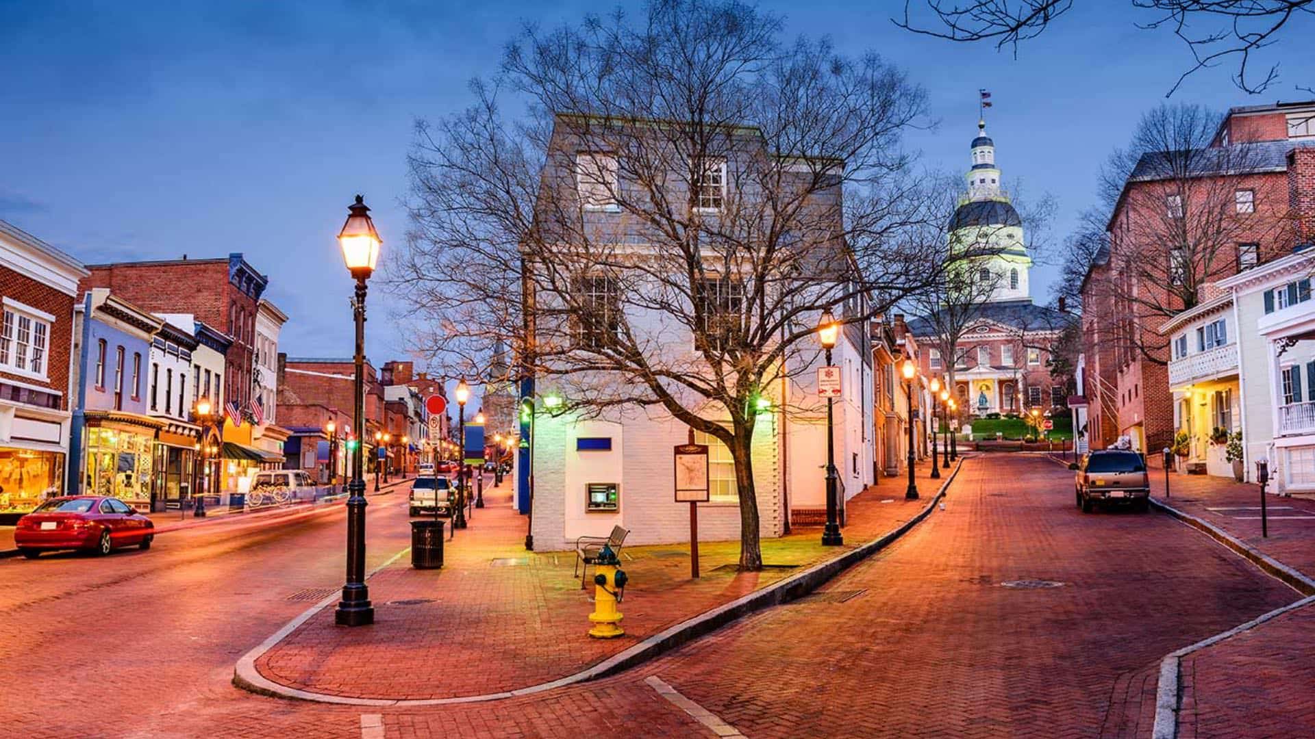 Small town city brick streets with lighted buildings and street lamps at dusk