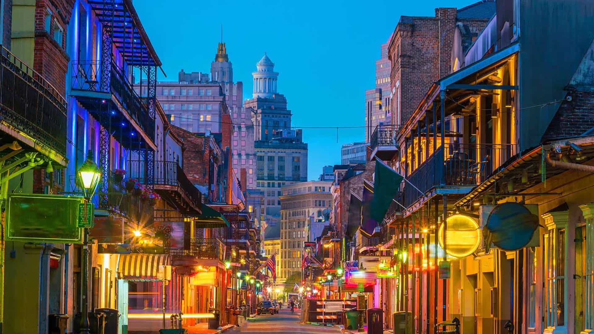 View of a downtown street with small and tall buildings all lighted up at dusk