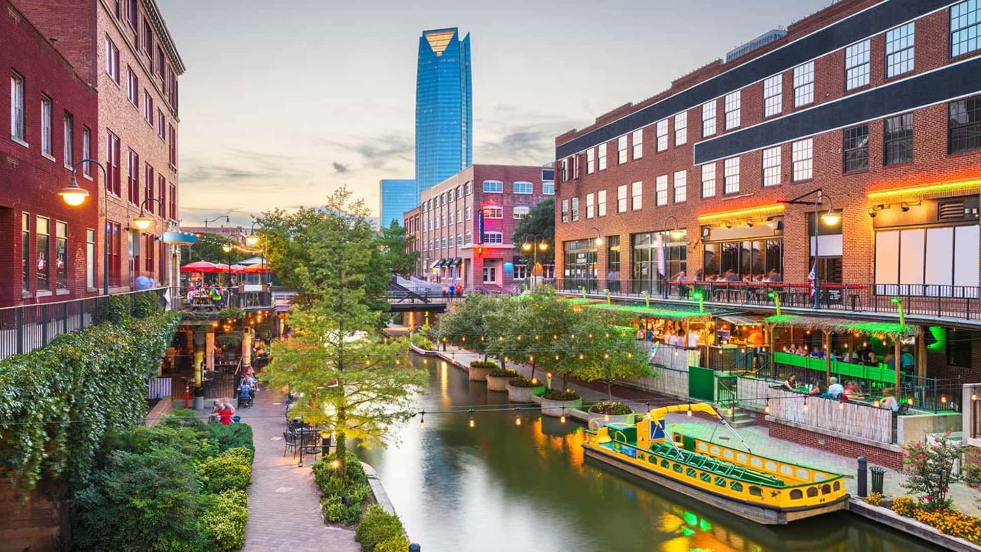 Small river running through a downtown city all lighted up at dusk