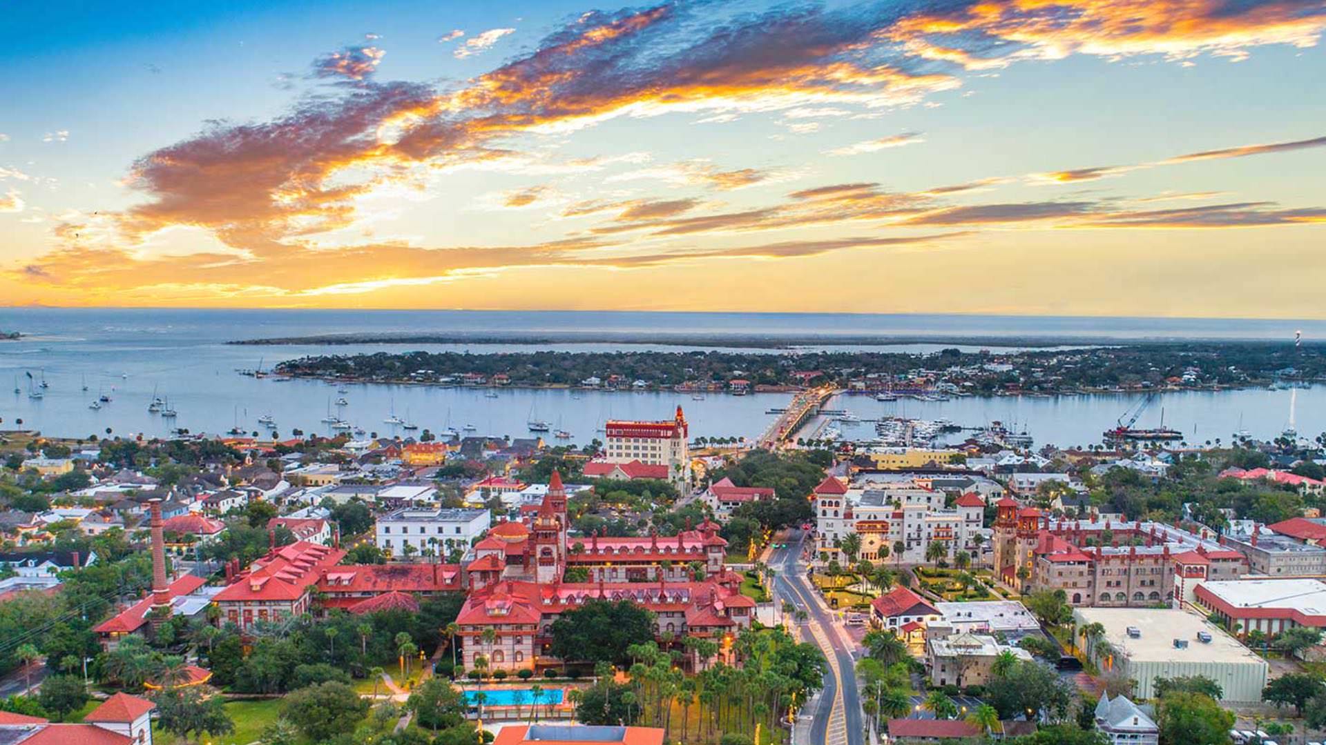 Aerial view of a coastal town with the ocean and setting sun in the background