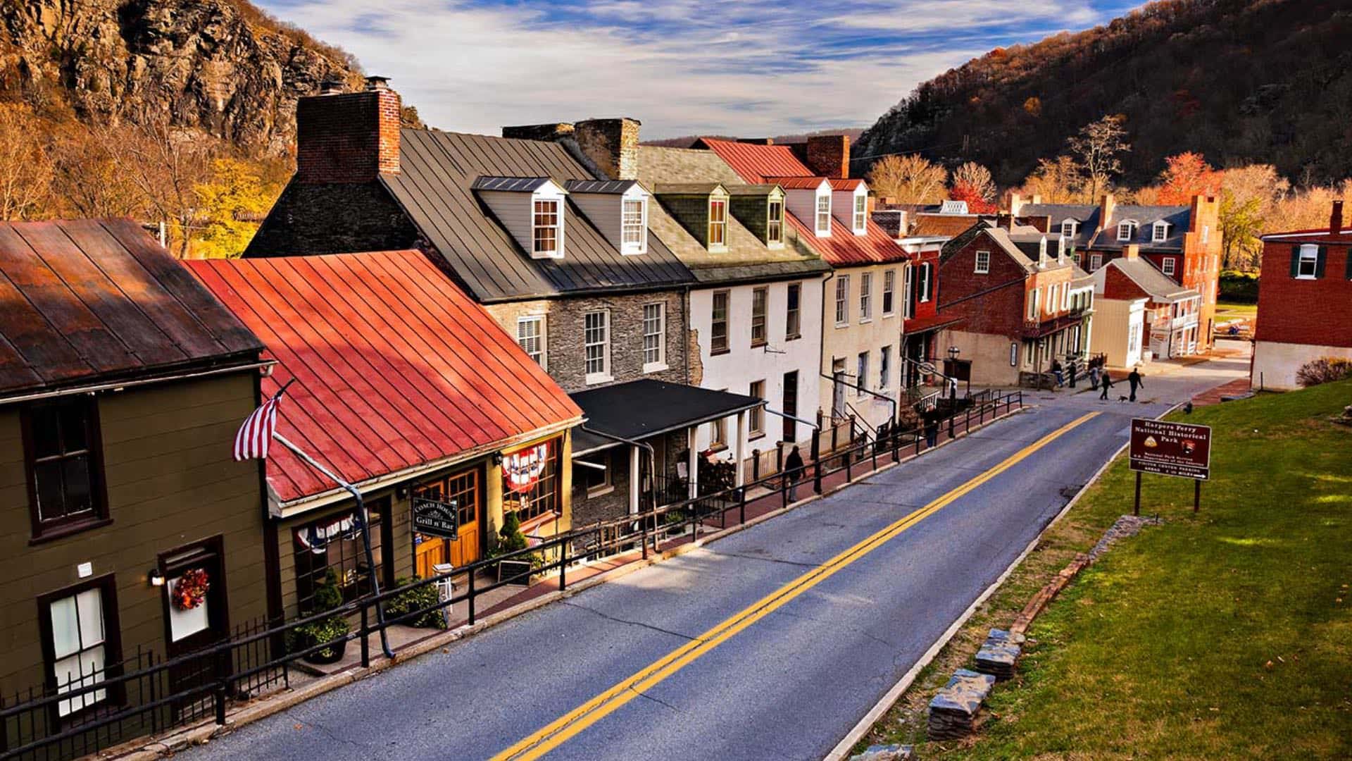 Small historical buildings and park with rocky cliffs in the background