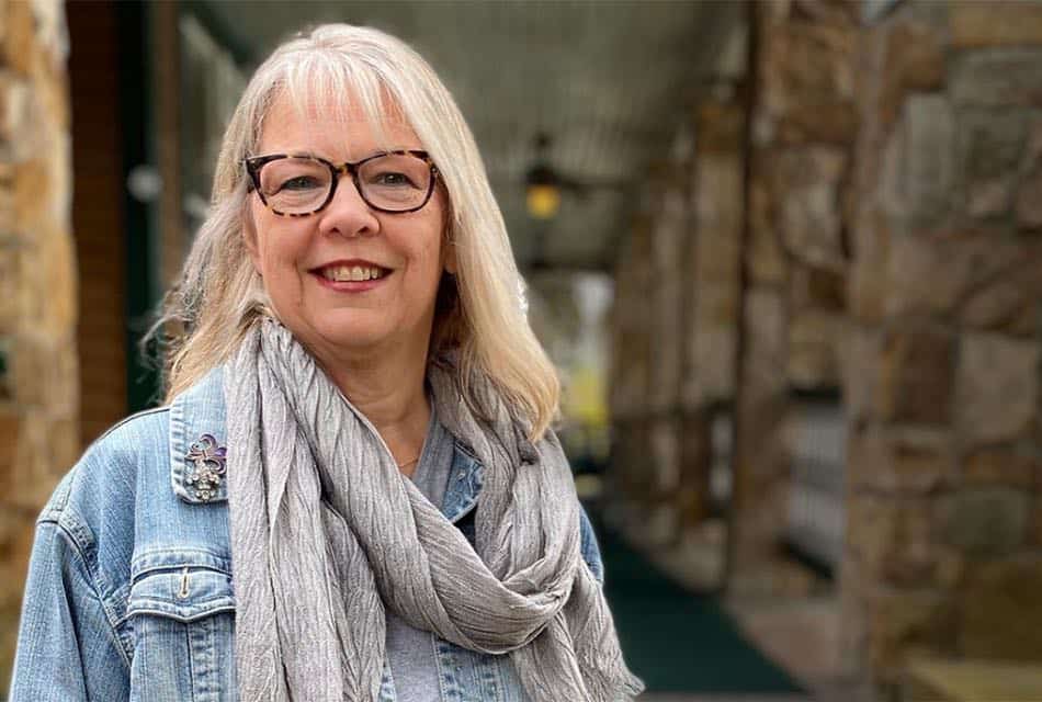 Woman wearing dark-framed glasses, jean jacket and gray scarf